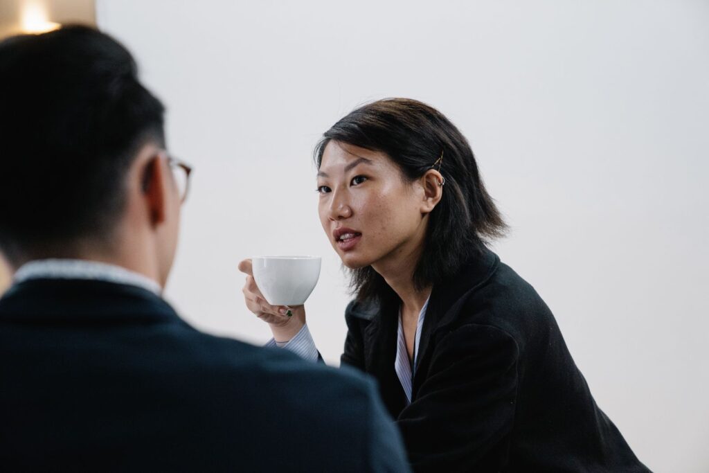 Two colleagues talking over coffee in a bright office
