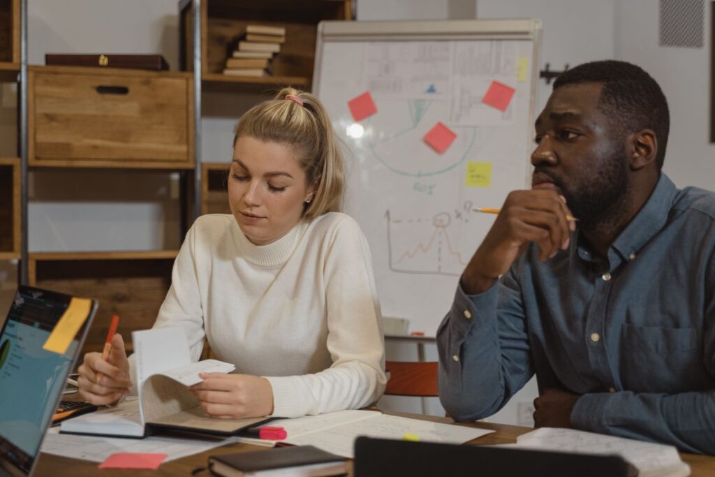 Coworkers reviewing notes in front of a whiteboard with sticky notes