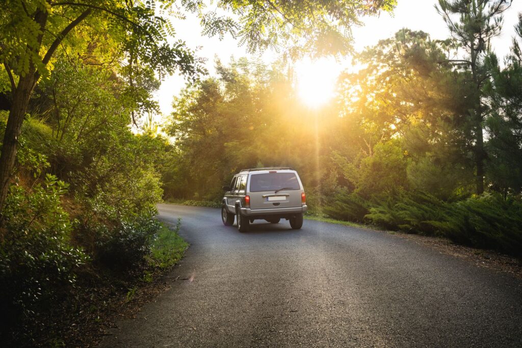 Car driving along a quiet tree lined road at sunset
